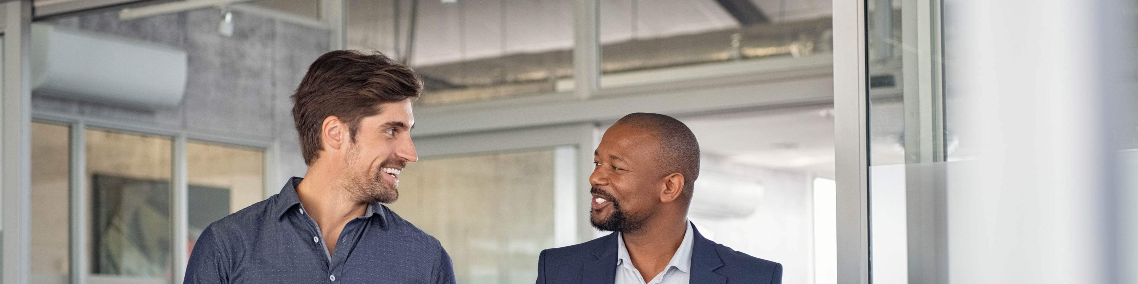 two men walking through an office, smiling