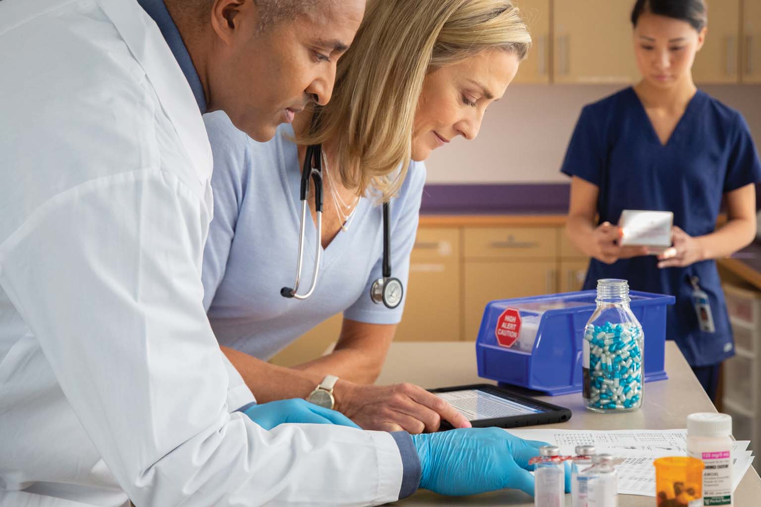 pharmacist with doctor and nurse in lab viewing tablet