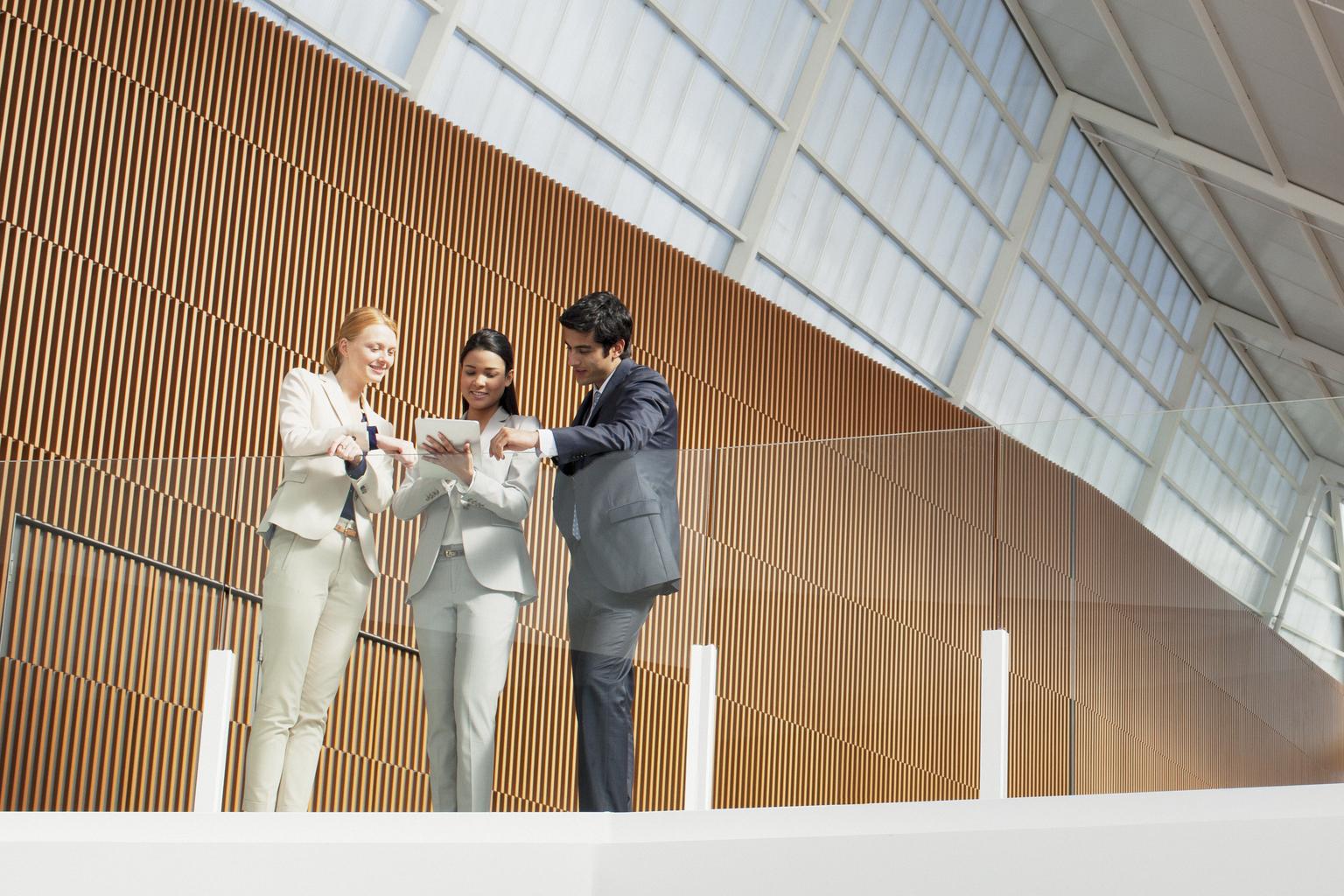 Three colleagues looking at ipad in office hall