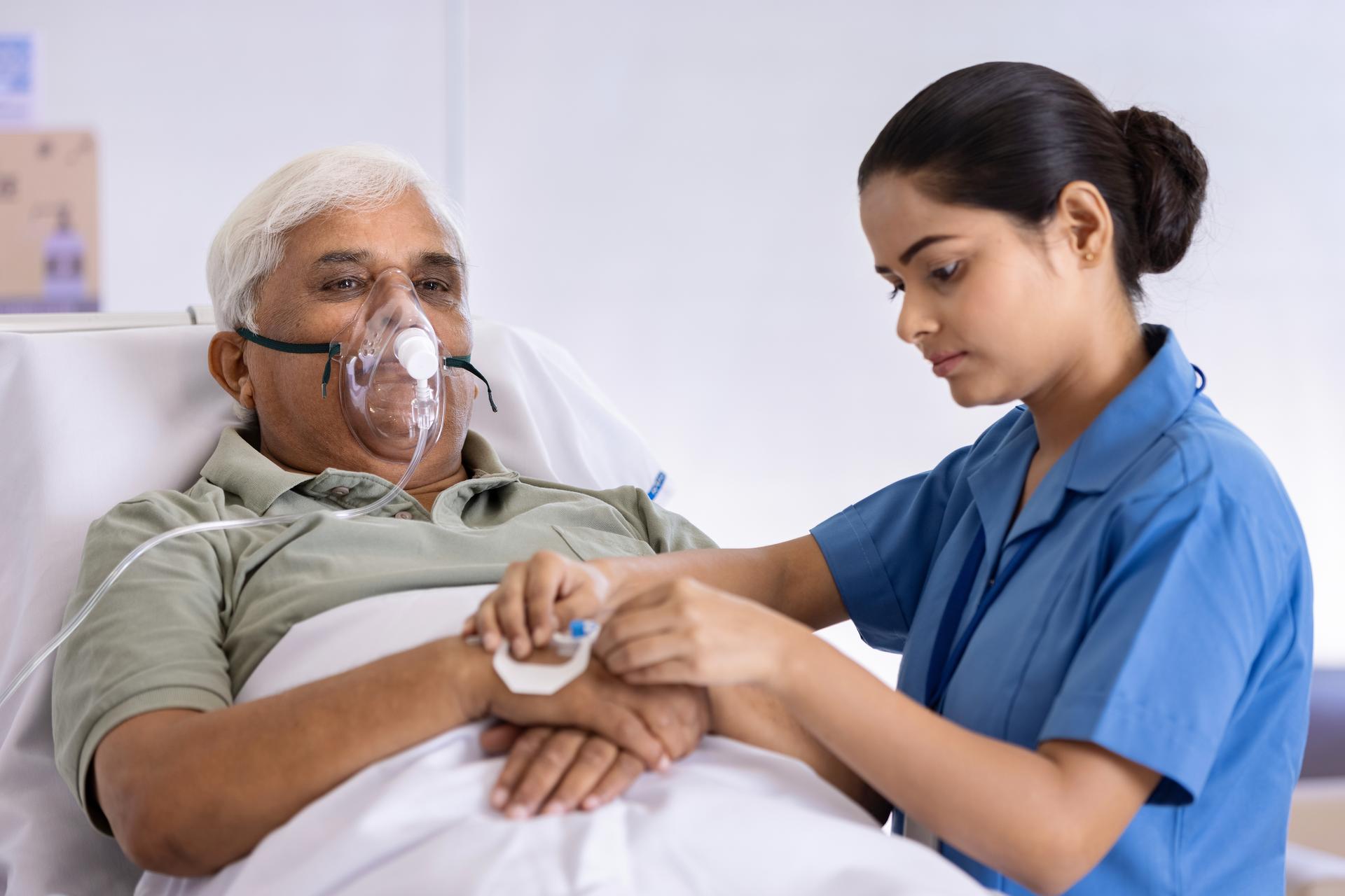 A nurse sets up an IV for patient in a hospital bed