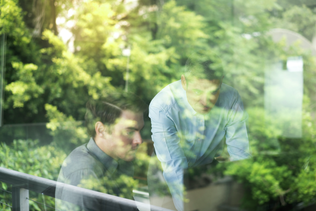 Businessmen using computer seen through window