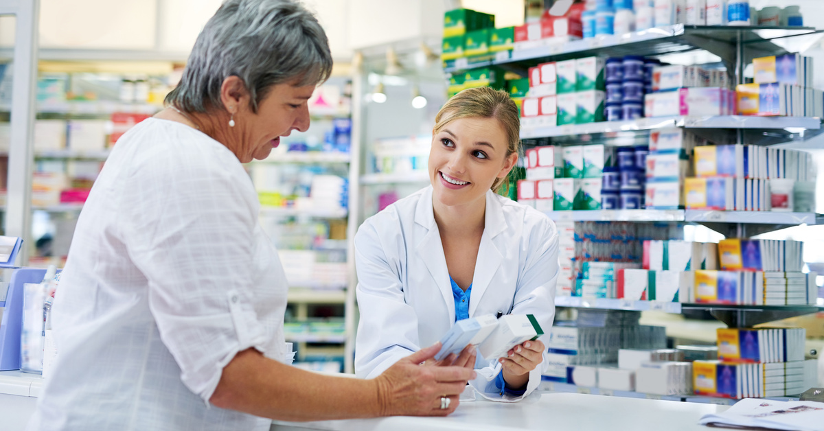 Pharmacist explaining medicine to a woman in the pharmacy for pharmaceutical healthcare prescription