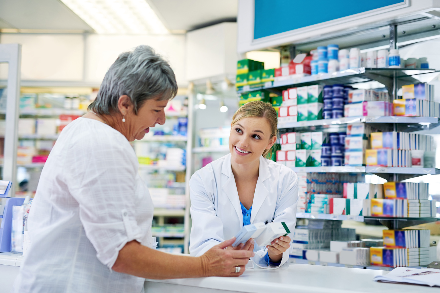 Pharmacist explaining medicine to a woman in the pharmacy for pharmaceutical healthcare prescription