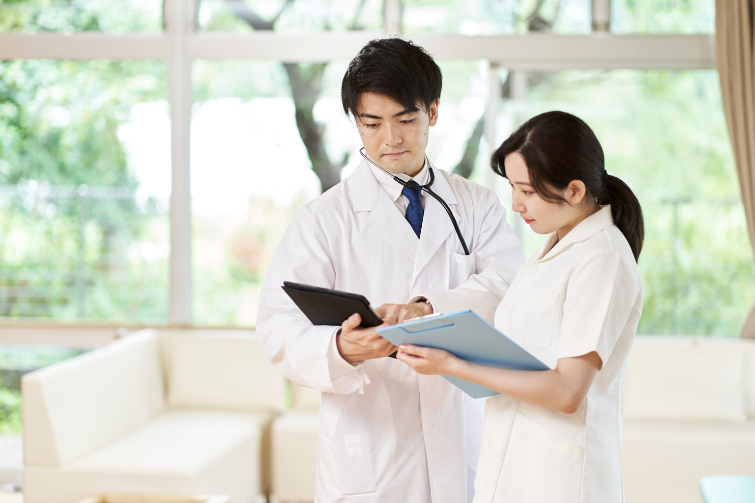 Doctor and nurse having a meeting holding tablet and clipboard