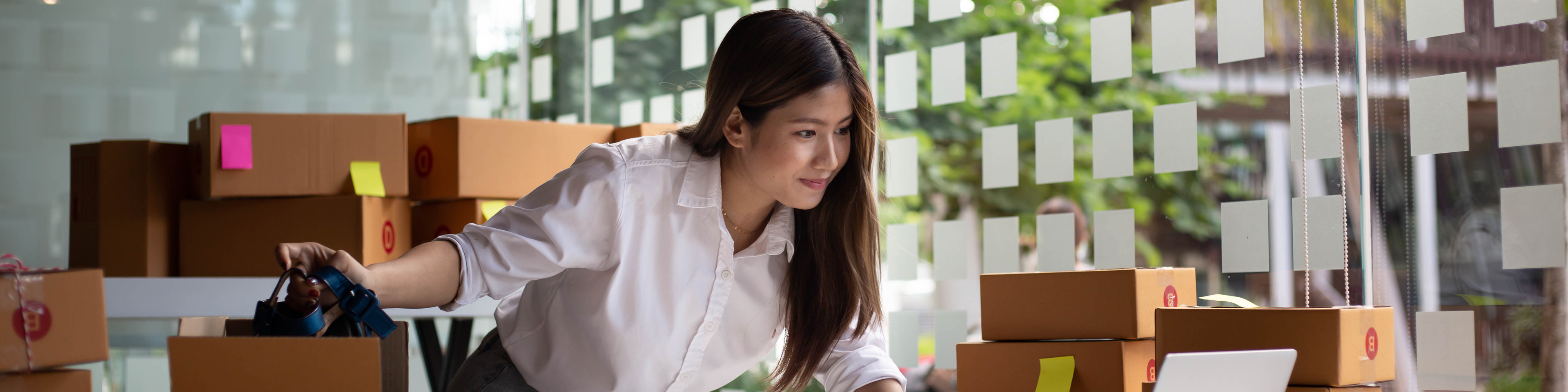 Female entrepreneur checks online orders to prepare to pack boxes