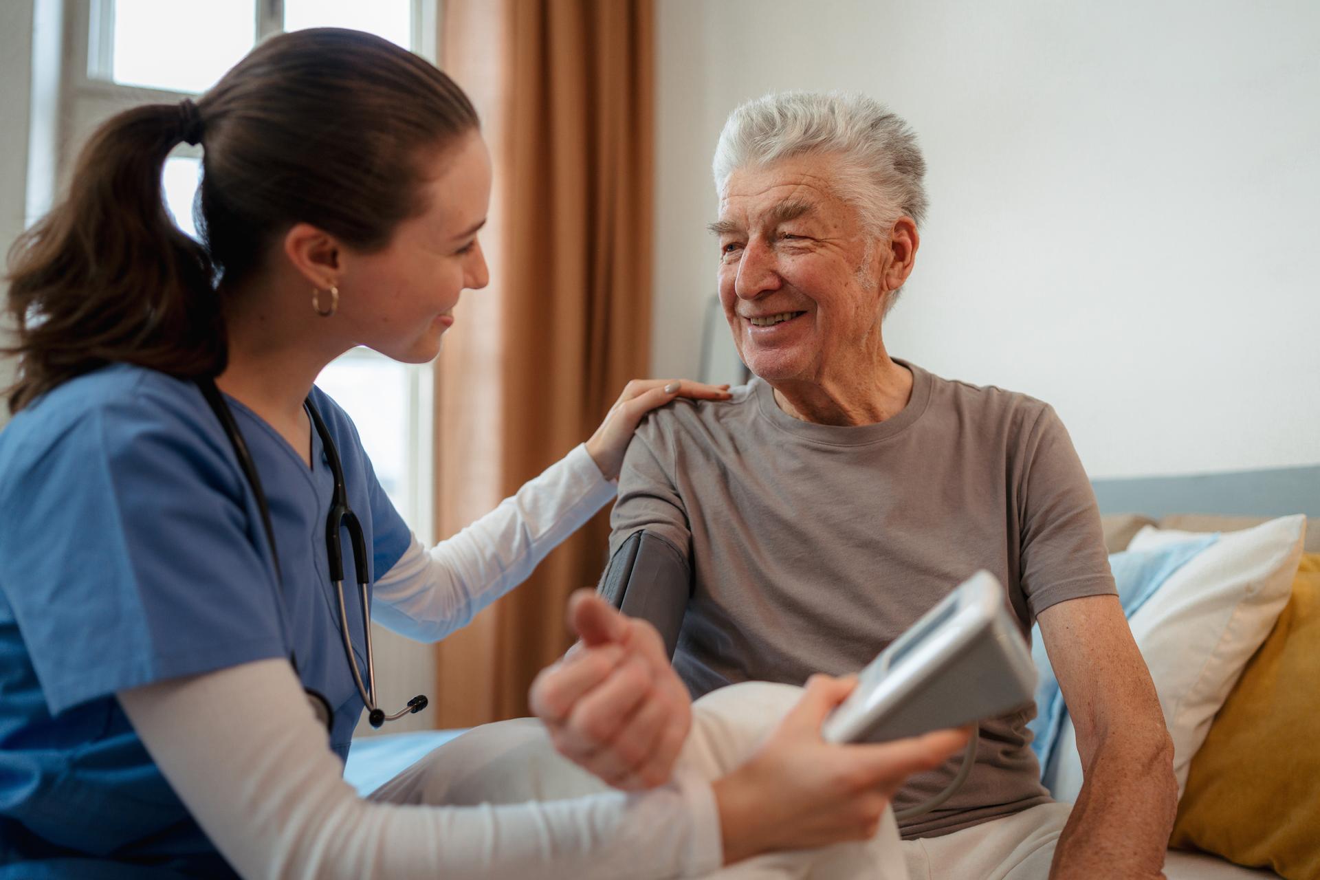 Senior male patient smiles at nurse taking blood pressure
