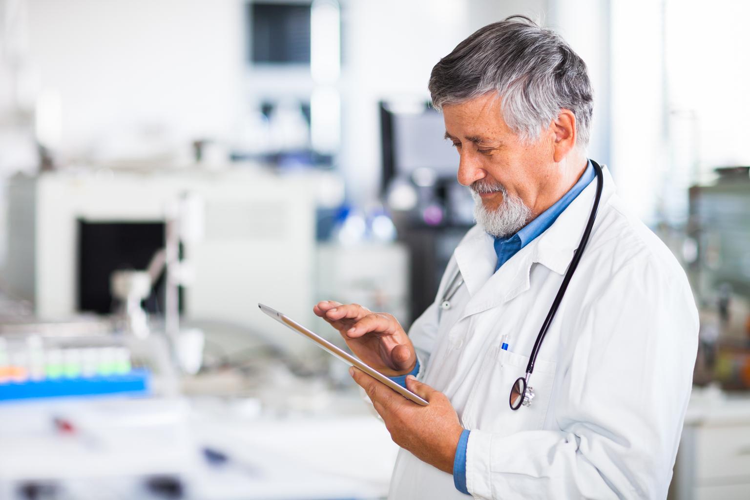 Senior doctor using his tablet computer at work