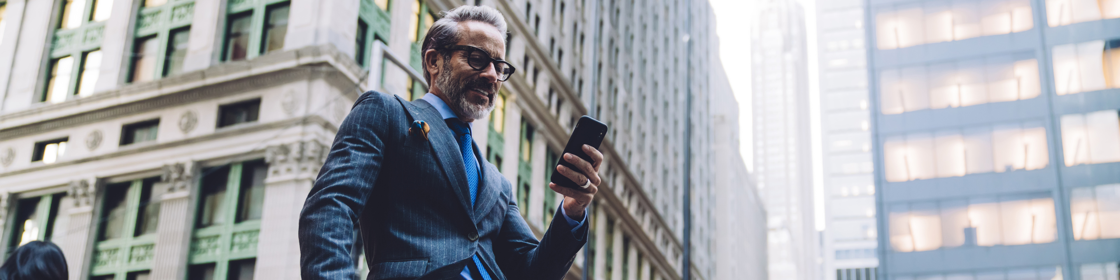 smiling-businessman-on-city-street-leaning-on-handrail