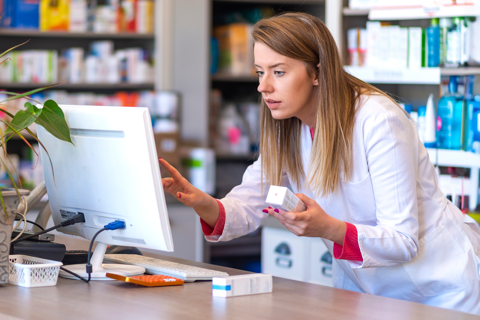 Pharmacist making prescription record through computer in pharmacy