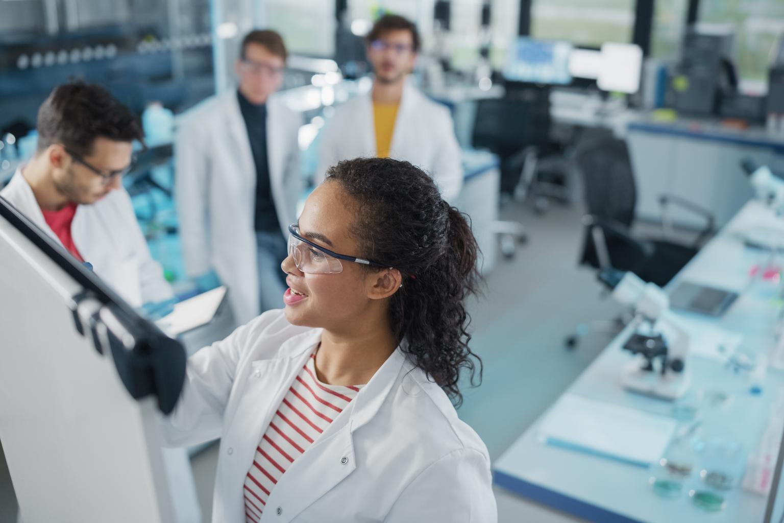 Lab scientists working in a group using a white board to brainstorm ideas