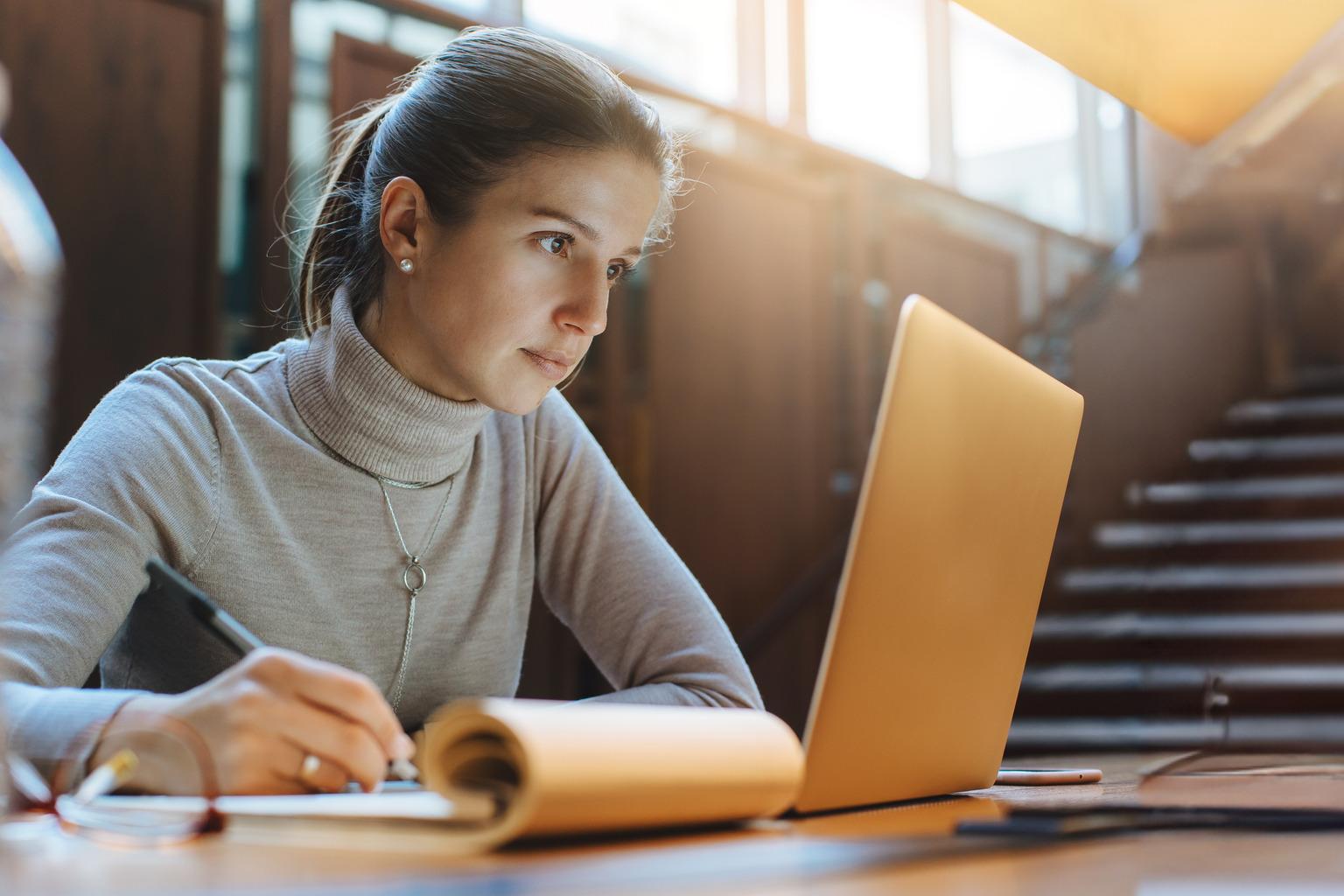 Portrait of young business woman using laptop at library