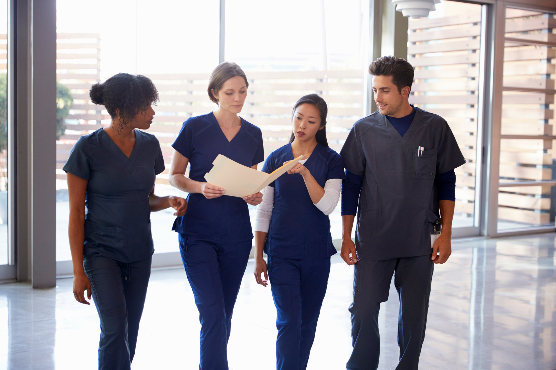 Healthcare colleagues discussing notes in hospital corridor