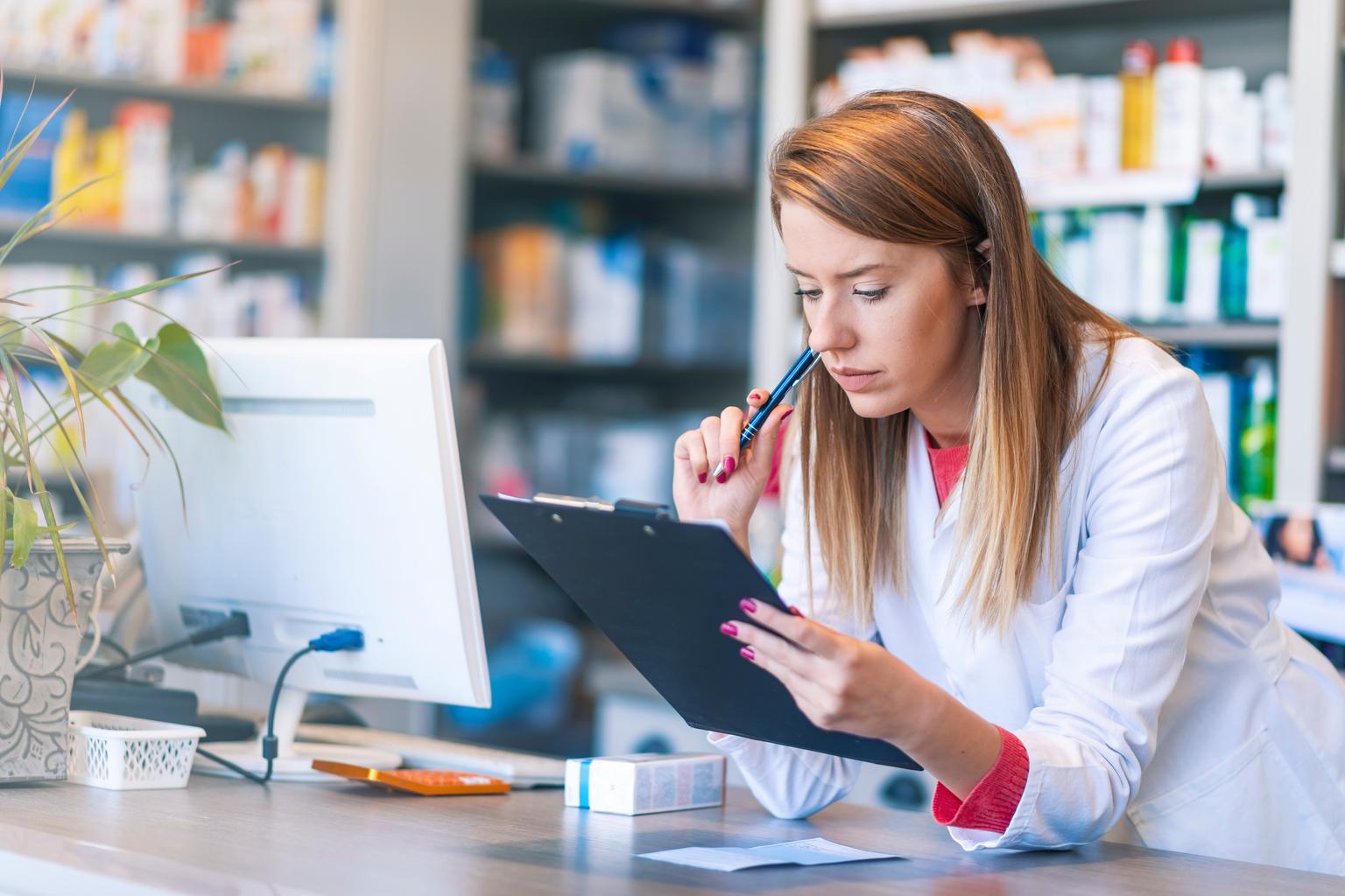 Pharmacist writing on clipboard at the hospital pharmacy.