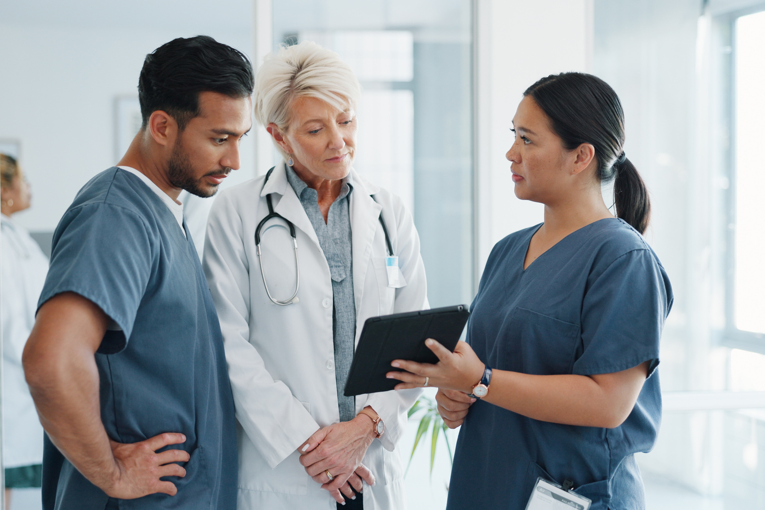 Medical professionals with touchscreen in conversation, collaboration or teamwork at clinic