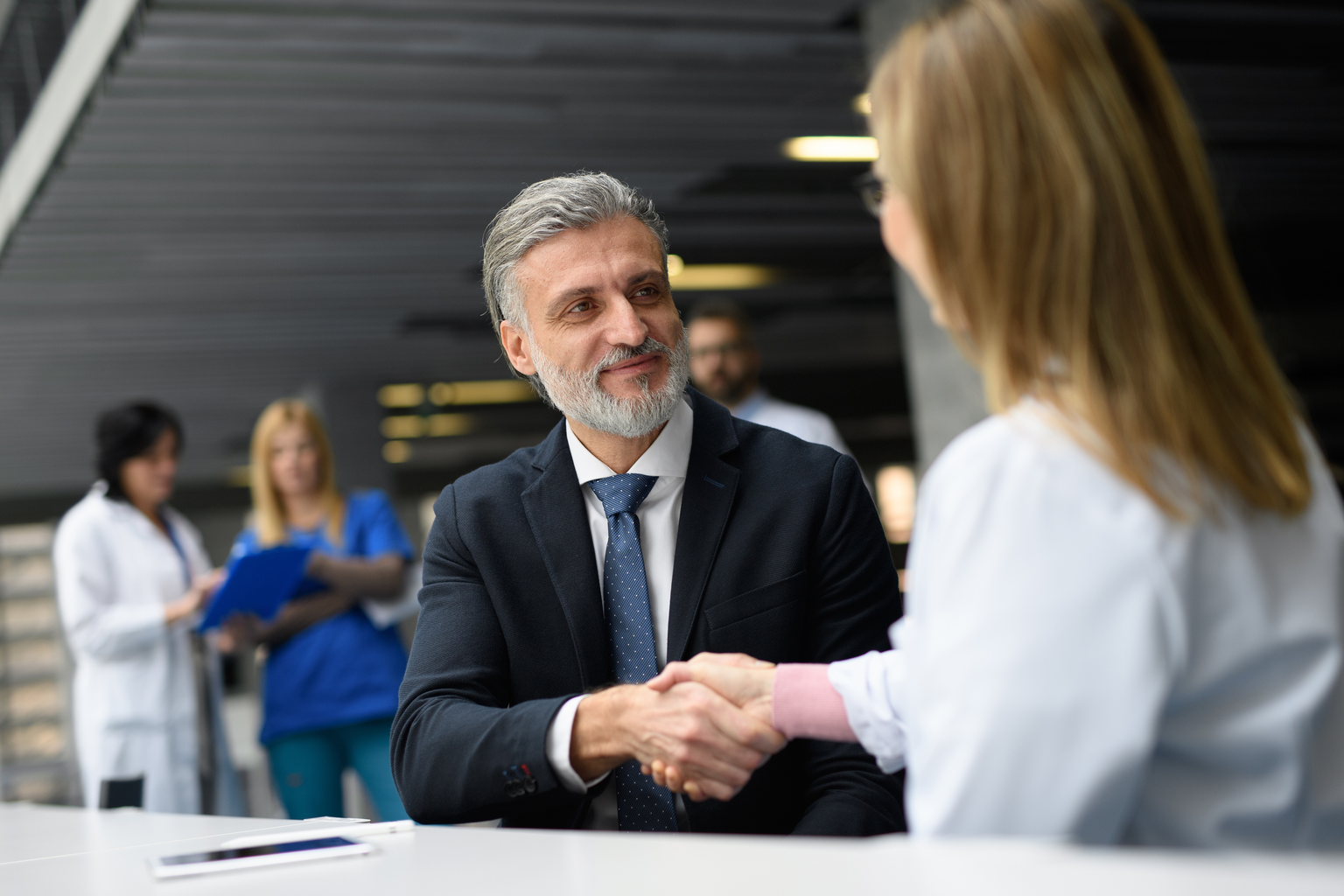 Doctor shaking hands with a business man in agreement in the hospital