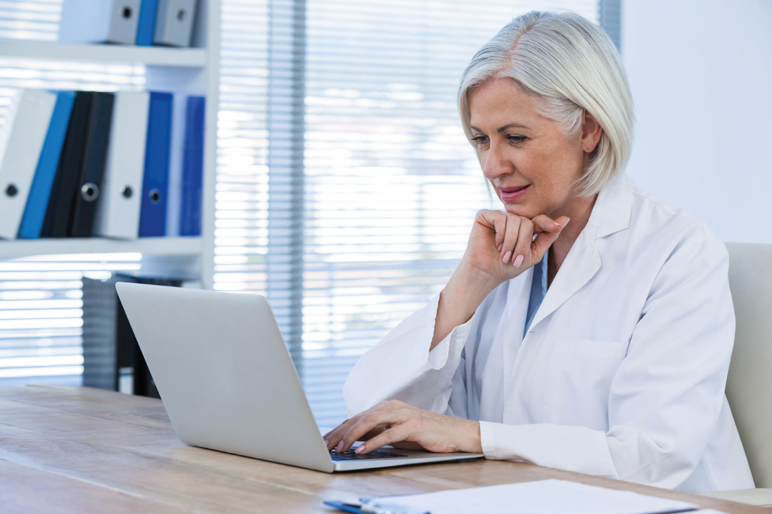 Starsza lekarka przed laptopem czyta o zmianach w prawie ochrony zdrowia w 2024 r.