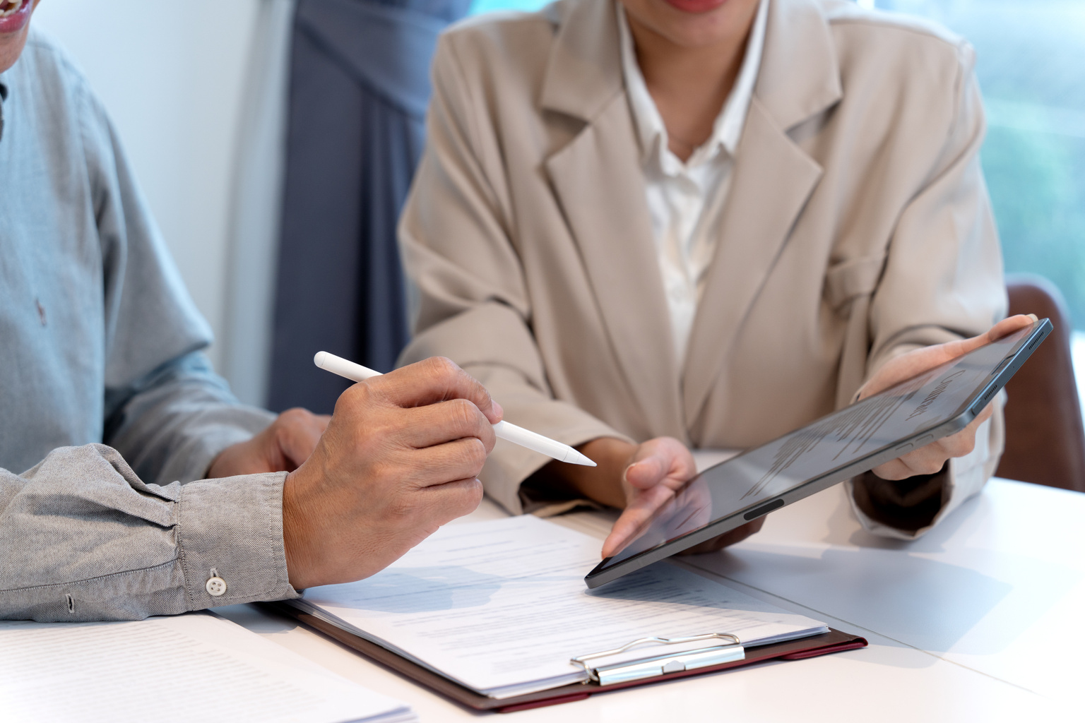 Woman handing an electronic document on a tablet for a businessman to sign