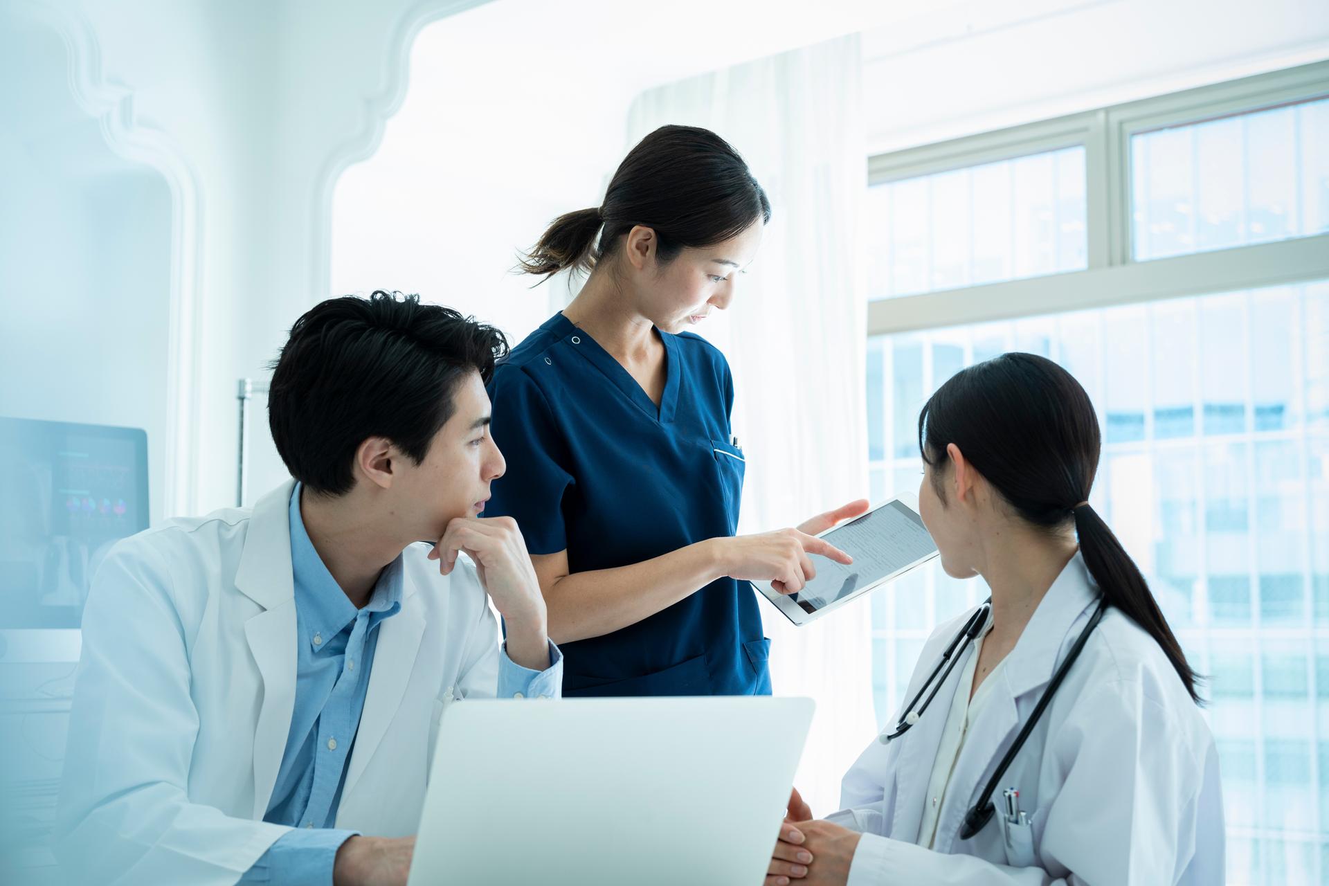 Doctors having a meeting while looking at a tablet and materials