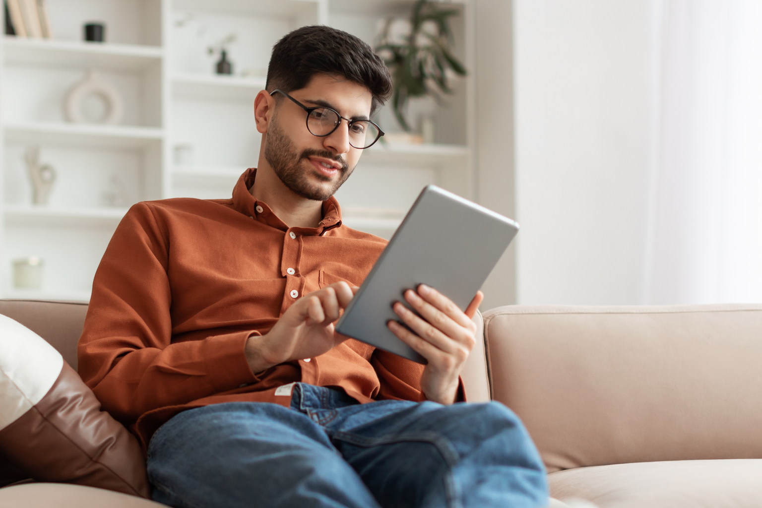 Man sitting on the couch using a tablet at home