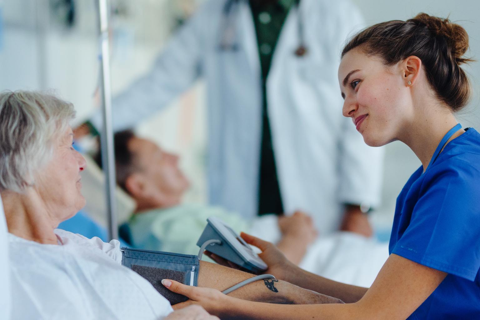 Nurse taking patient's blood pressure at bedside