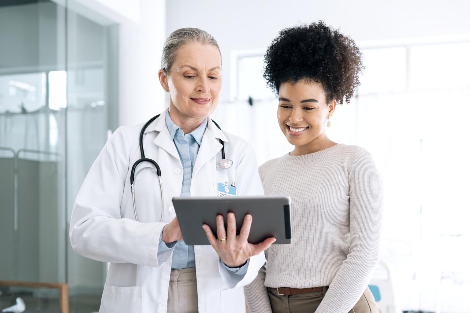 Group two, female doctor holding a tablet and providing consultation to female patient in the hospital AS655082378