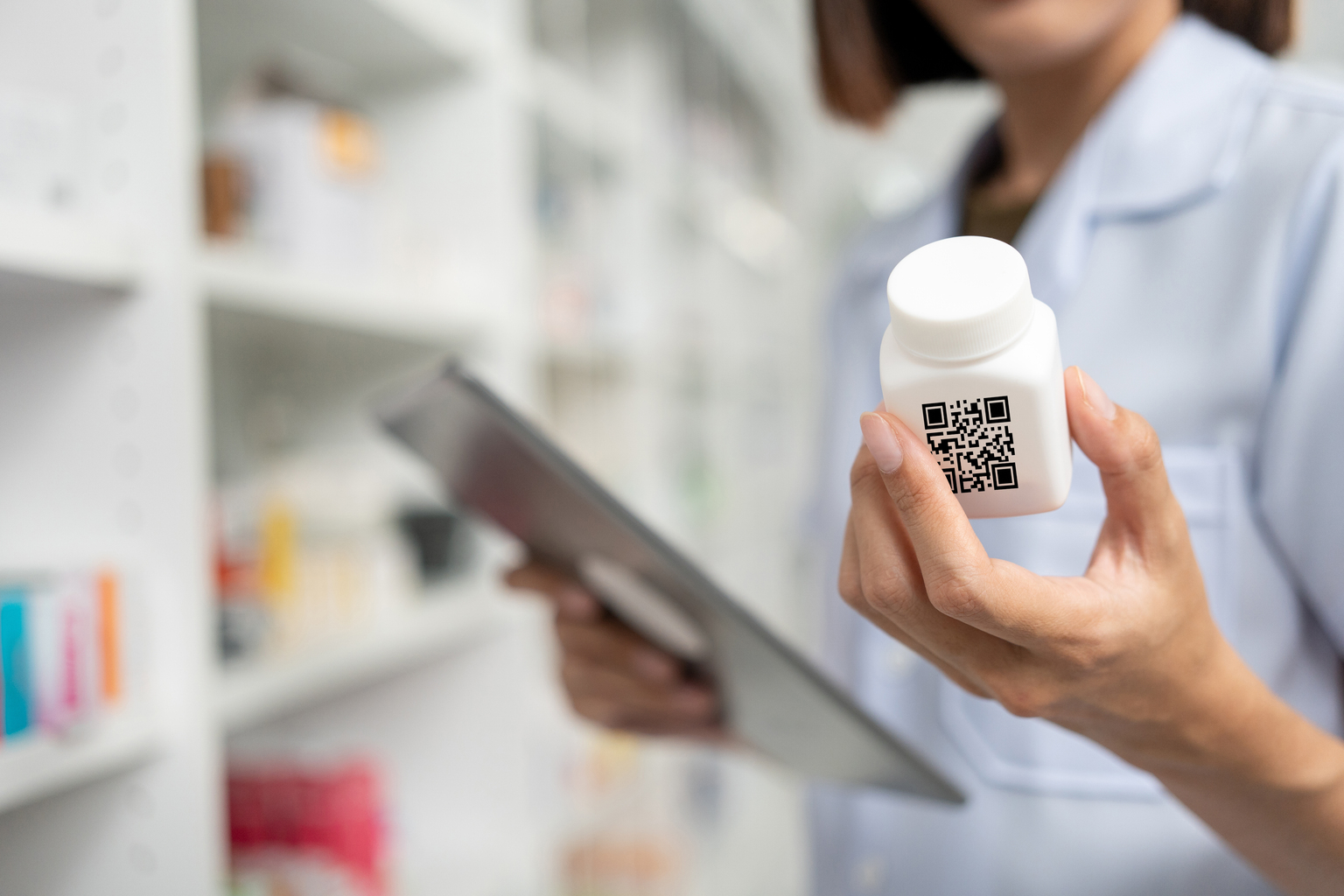 Close-up of woman's hands holding a medicine bottle near drug shelves