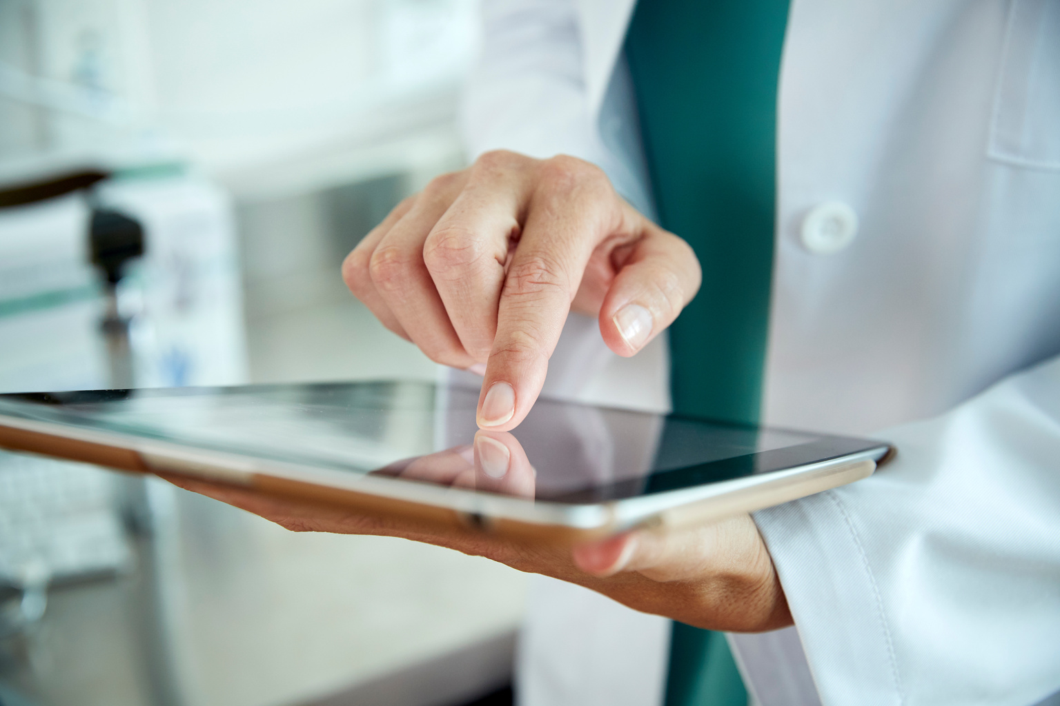 Close up image of physician using tablet.