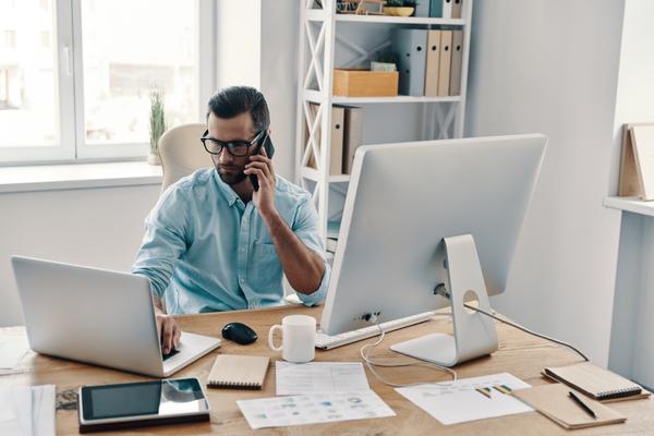 Businessman talking on the phone and working on computer while sitting in the office