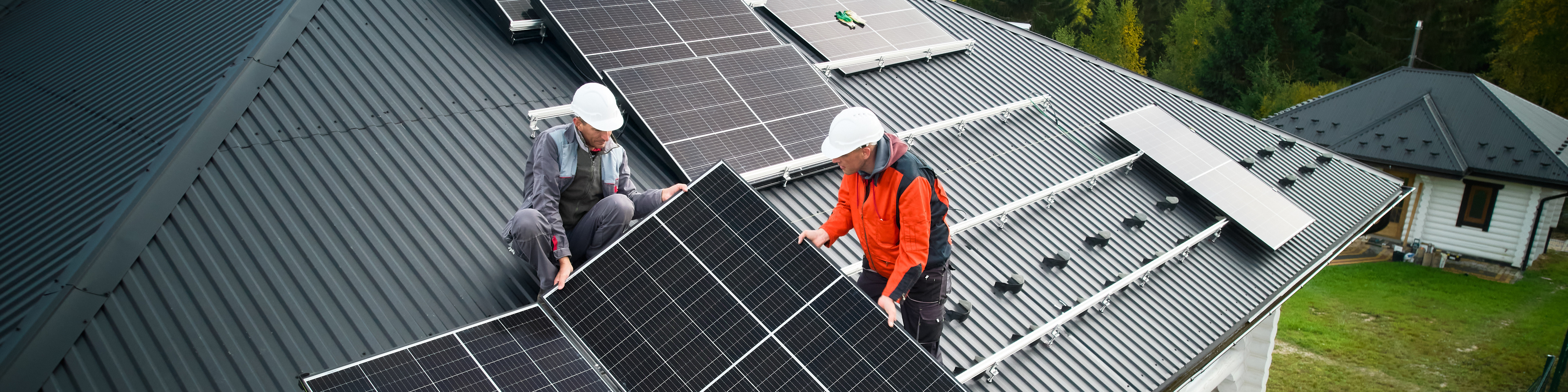 Two men installing solar panels on home