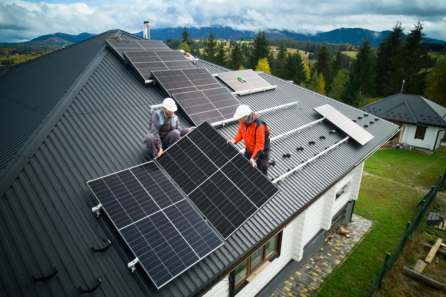 Two men installing solar panels on home