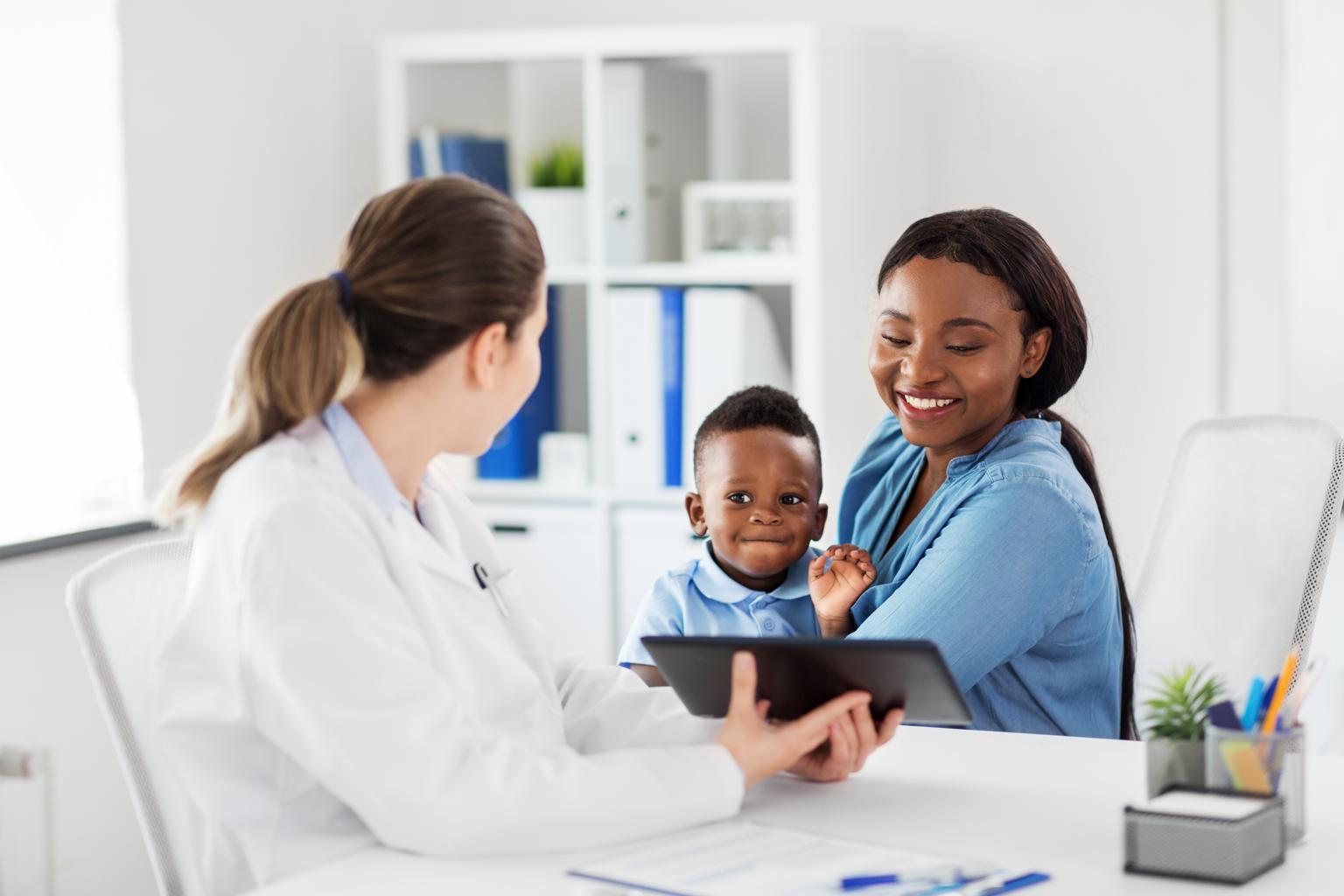 African american mother with baby son and caucasian doctor with tablet computer at clinic