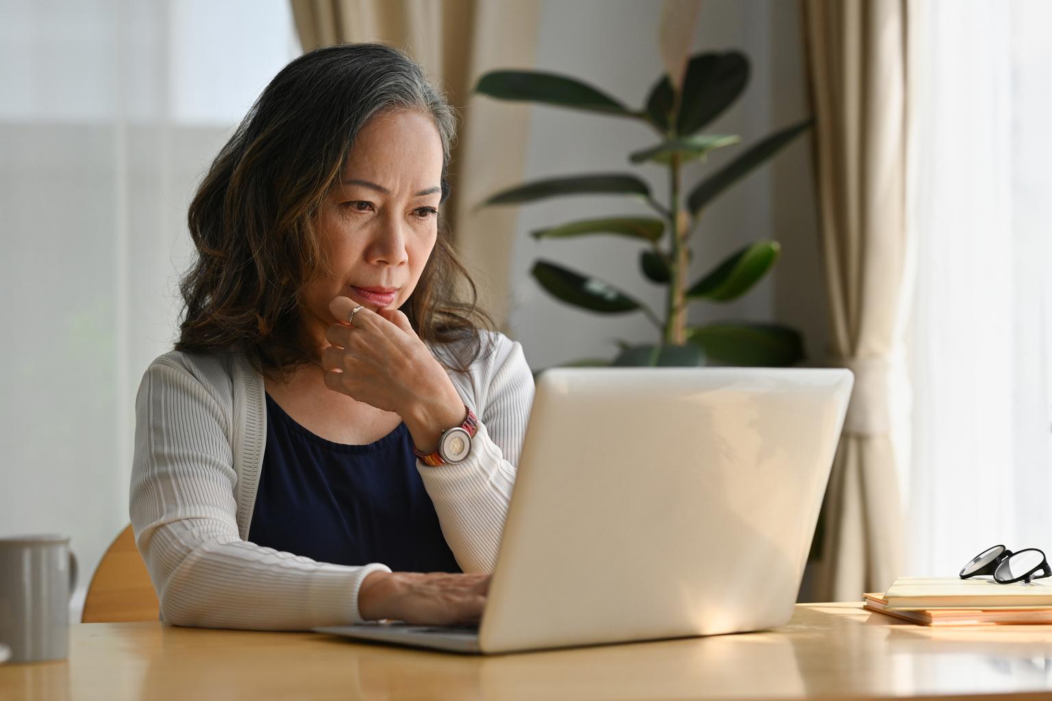 Portrait of senior woman working at home using a laptop