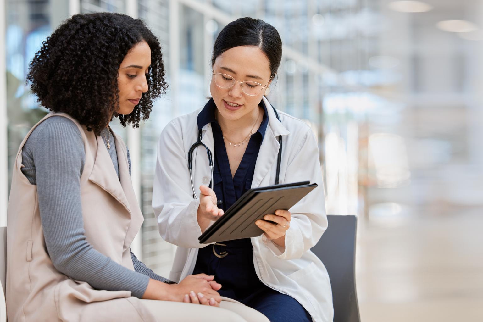 Female doctor consulting with a female patient using a tablet