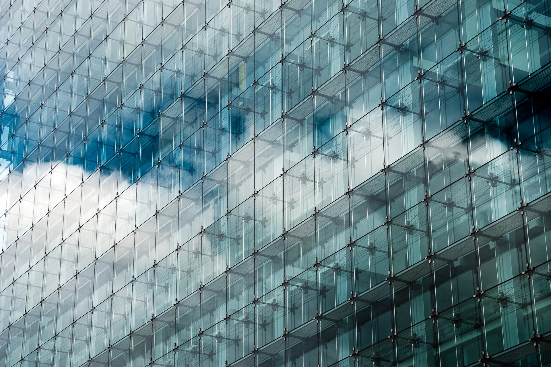 Blue, clouded sky reflected in glass frontage of urban