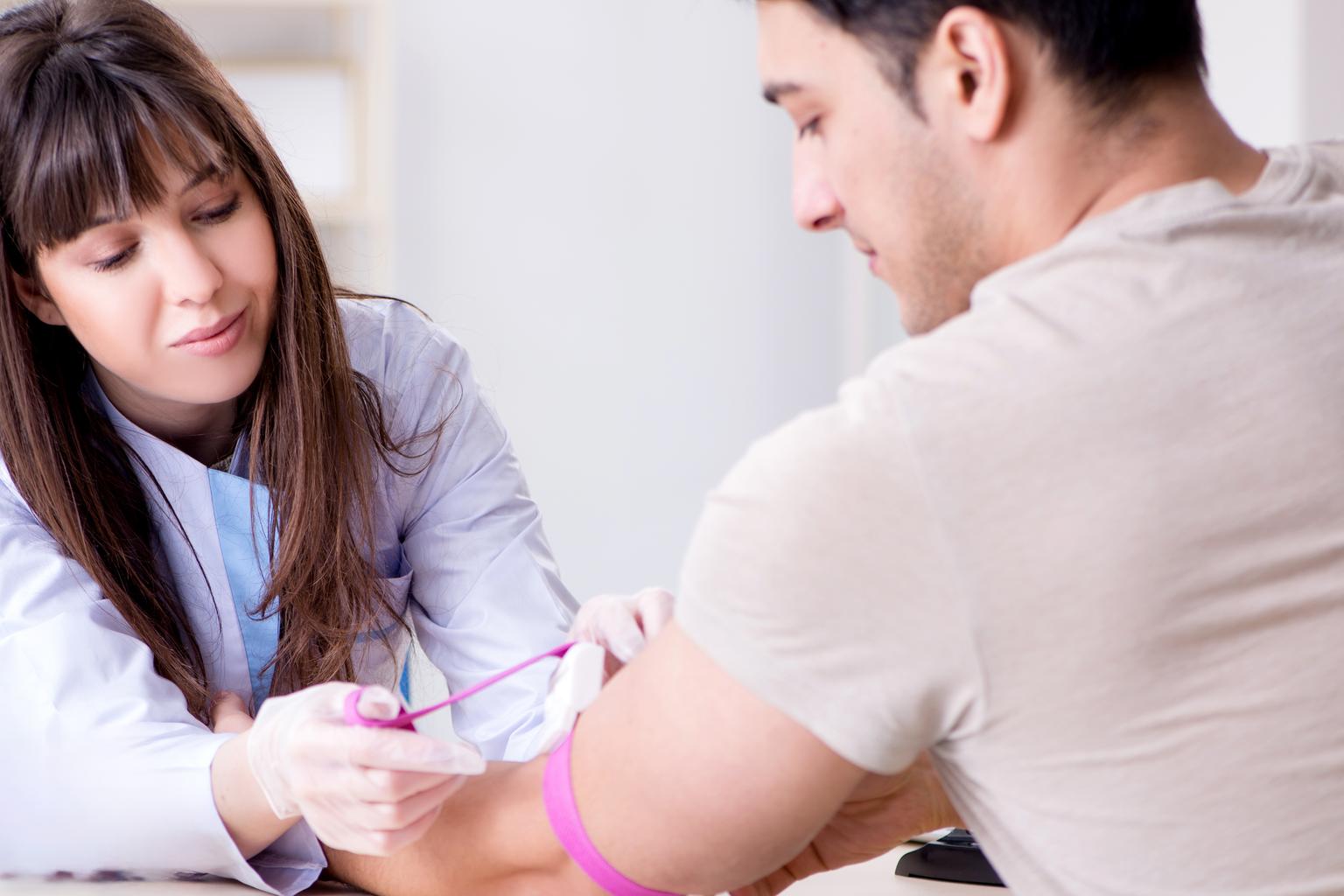 Female medical professional taking a blood sample from male patient for analysis