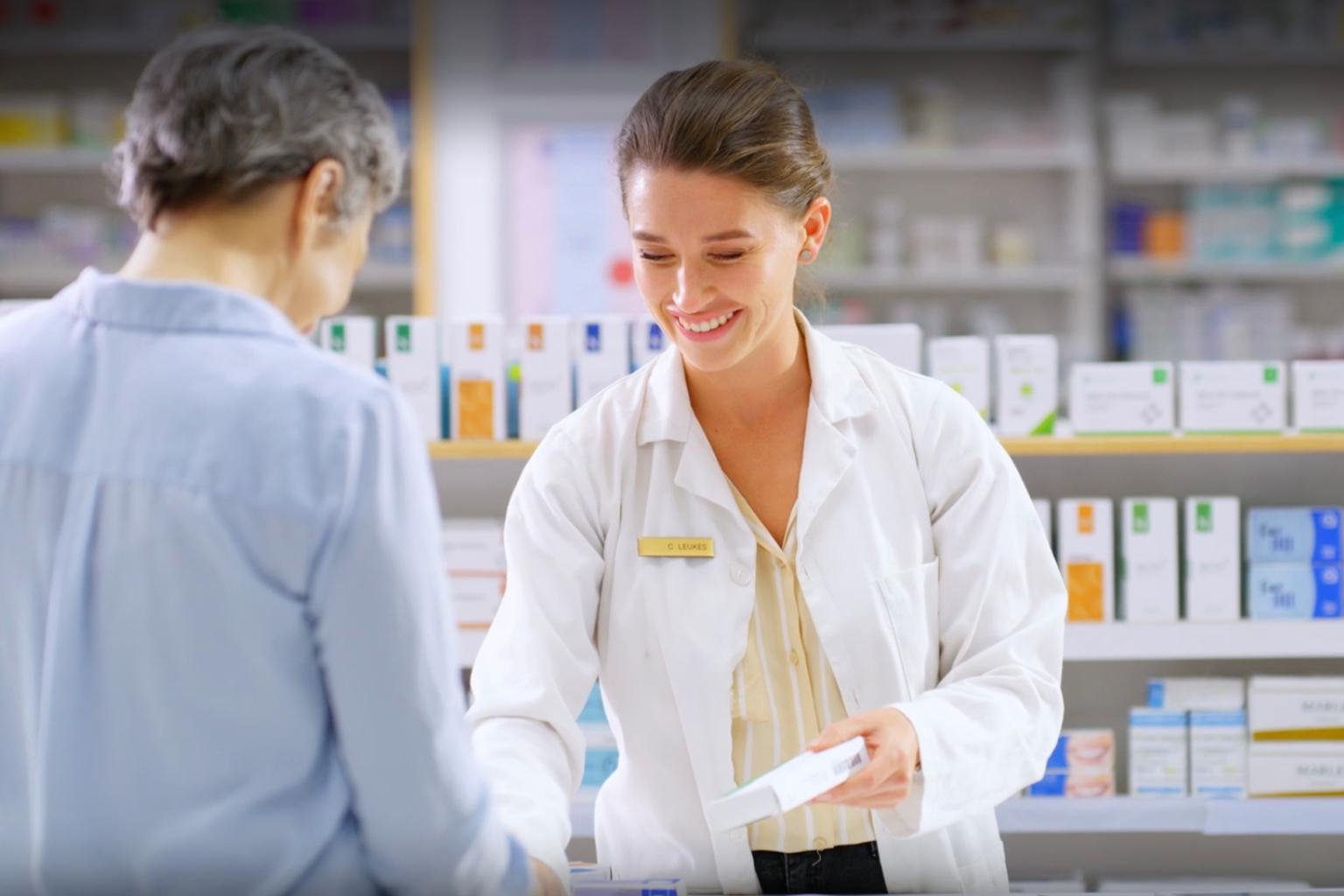 Woman pharmacist talking to customer over the counter at a pharmacy 