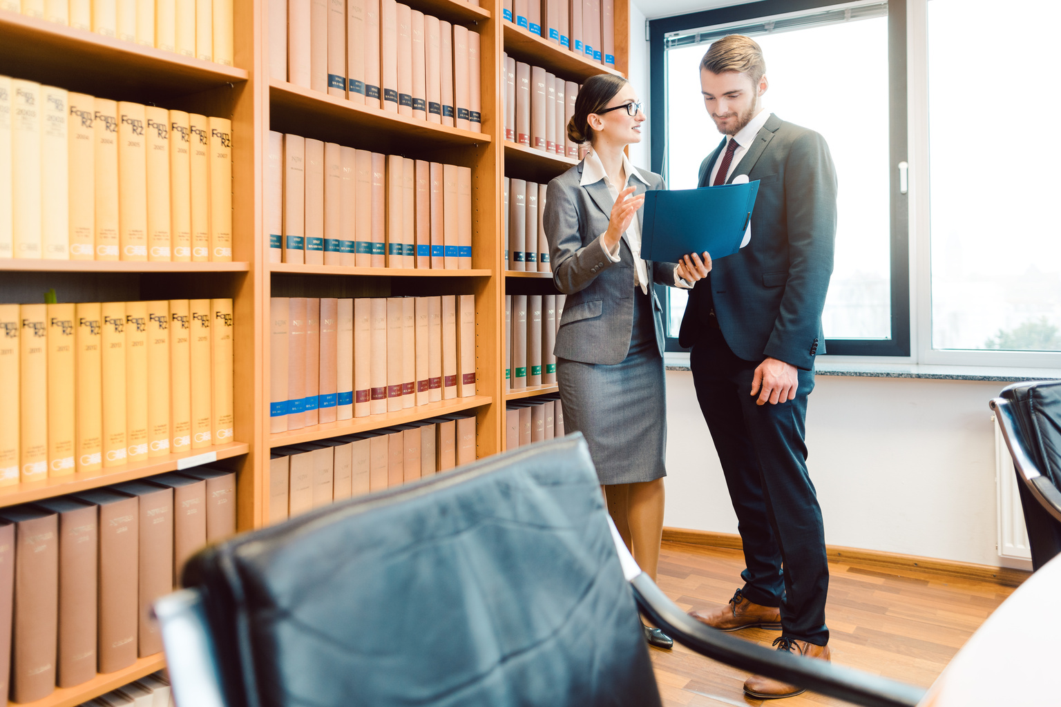 Lawyers in library of law firm discussing strategy in a case holding file