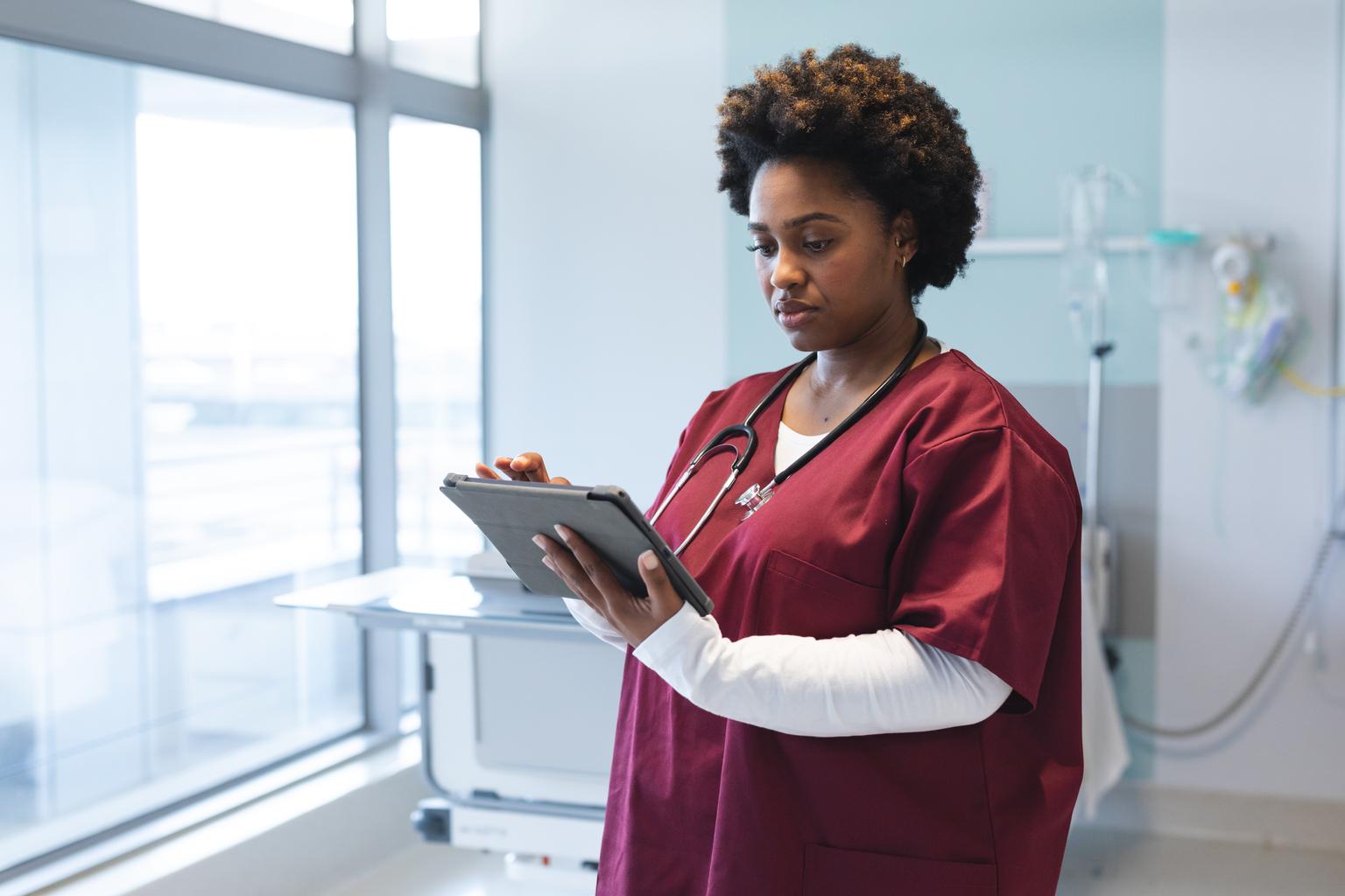 African American female doctor using a tablet in a hospital room AS617685837