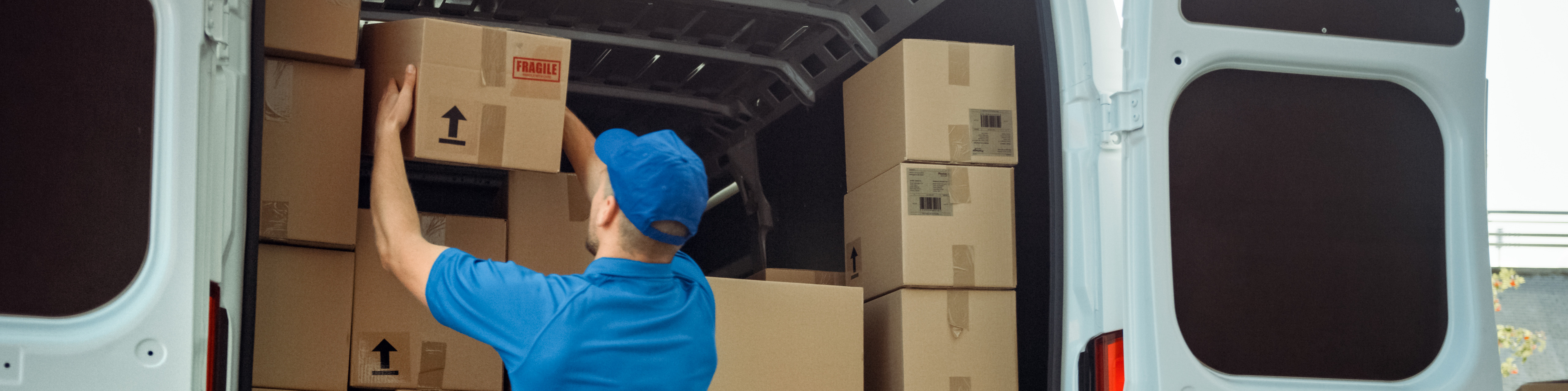 Courier Takes out Cardboard Box Package from Delivery Van Full of Parcels