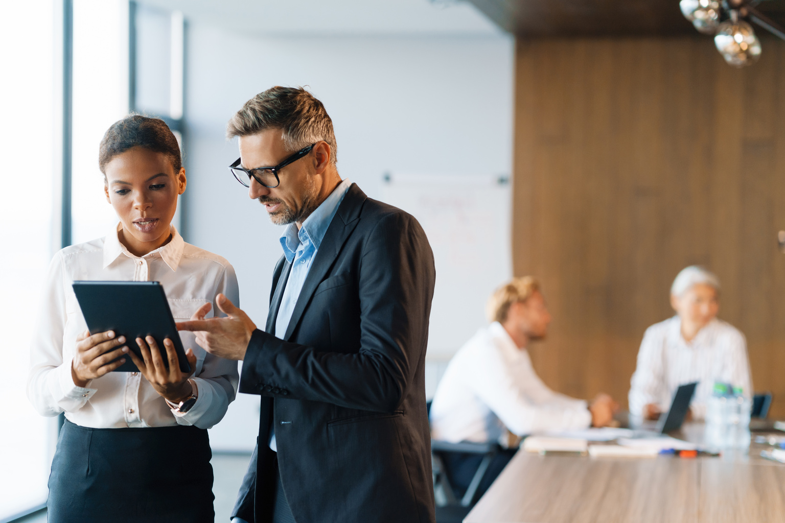 Auf dem Foto sind eine Frau und ein Mann im business Kontext zu sehen, die gemeinsam auf ein IPad schauen.