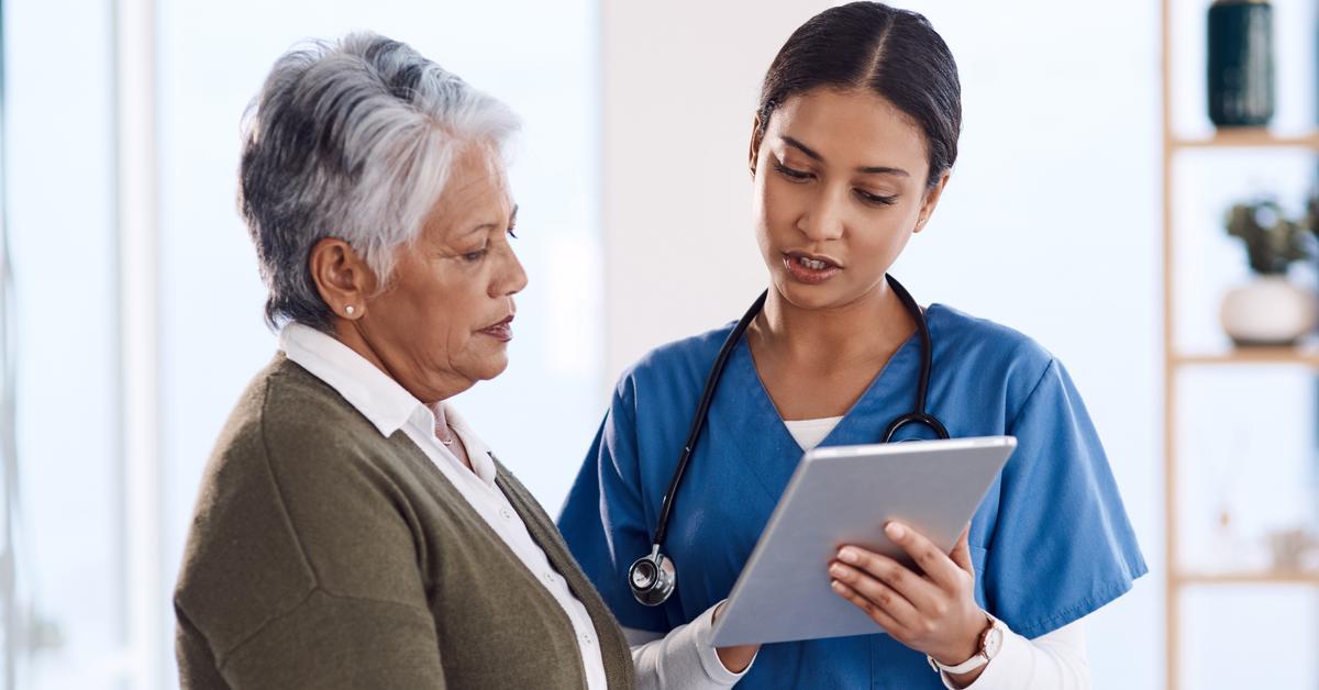 Young female doctor using a tablet during consultation with a senior woman