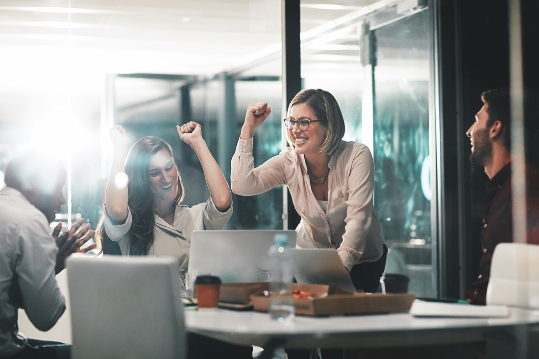 team celebrating a win in the office women cheering and raising hands