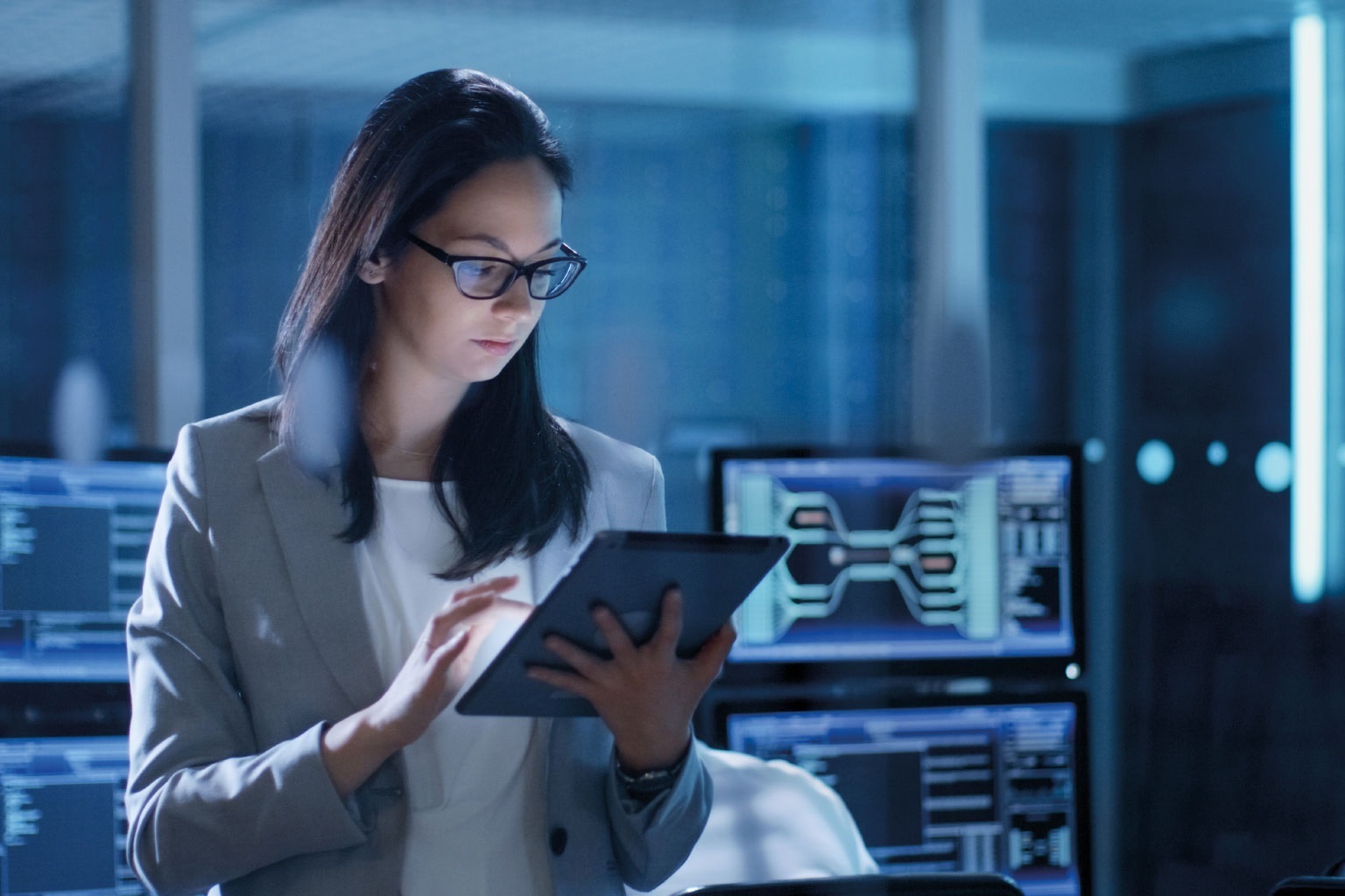 Young Female Government Employee Wearing Glasses Uses Tablet in System Control Center