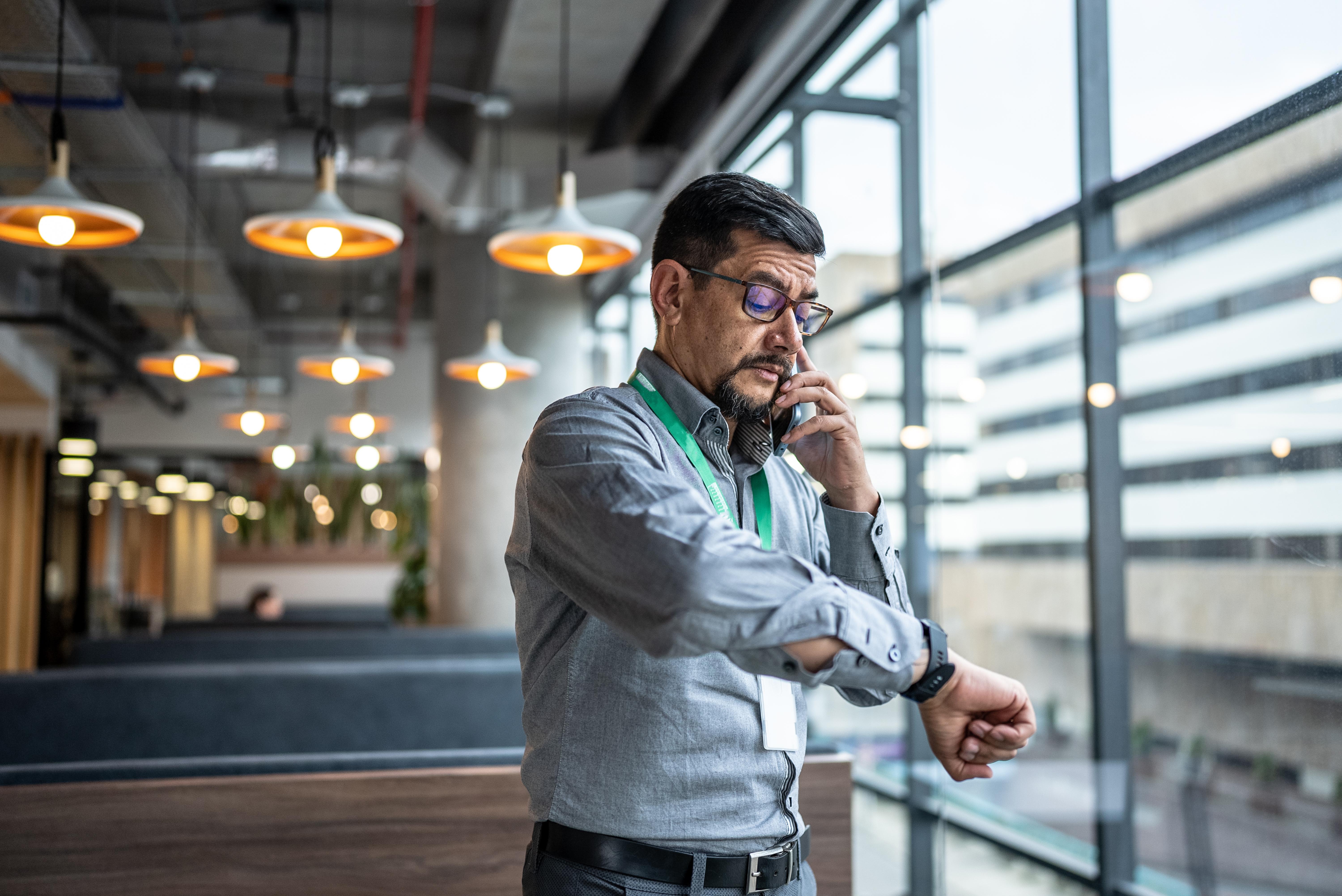 Business man checking the time in the office while calling