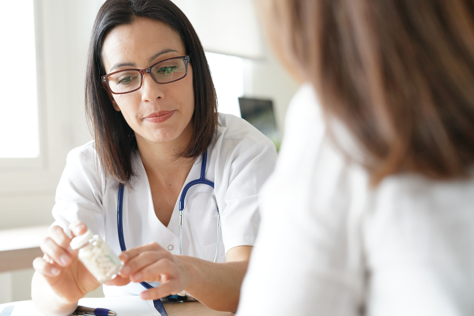 portrait-female-doctor-prescribing-medication-holding-pill-bottle-AS-196171746