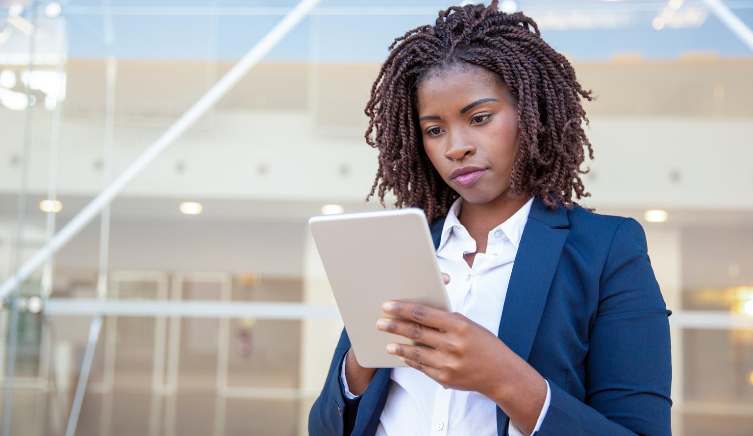 A focused business women using app on digital tablet outside.