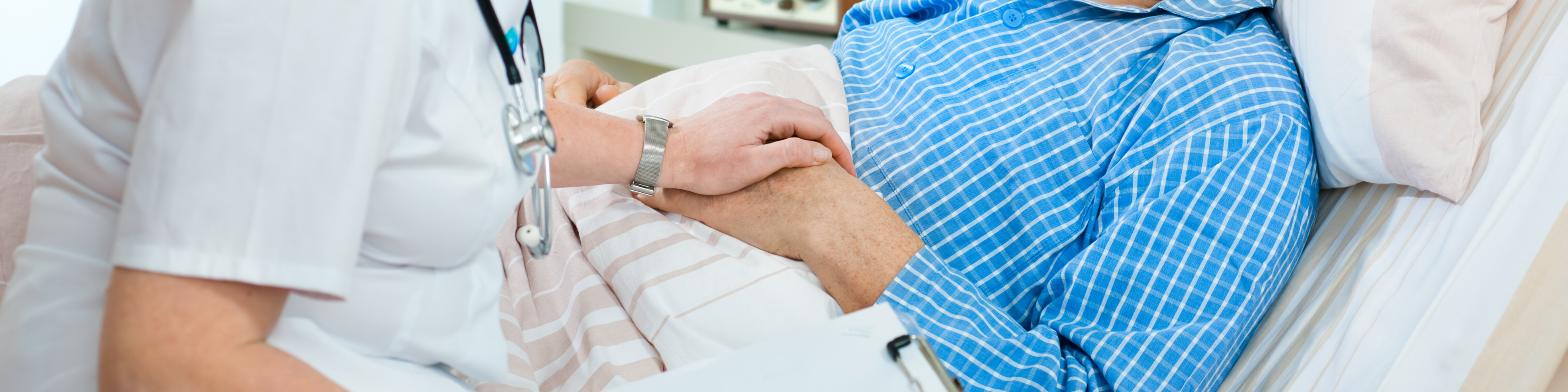 Nurse comforting a sick patient beside his hospital bed