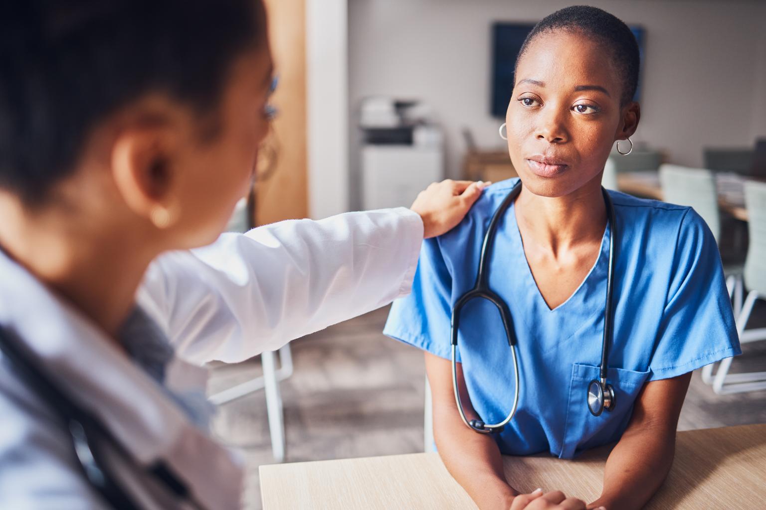 A female doctor gives advice and support to a nurse in hospital setting.