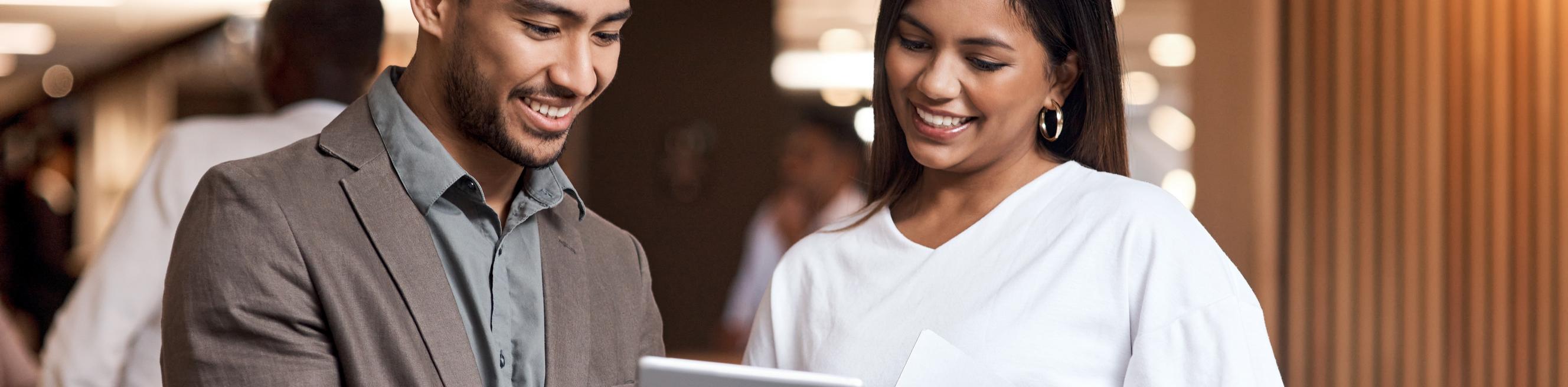 A businessman and woman in a conference focused on a digital tablet.