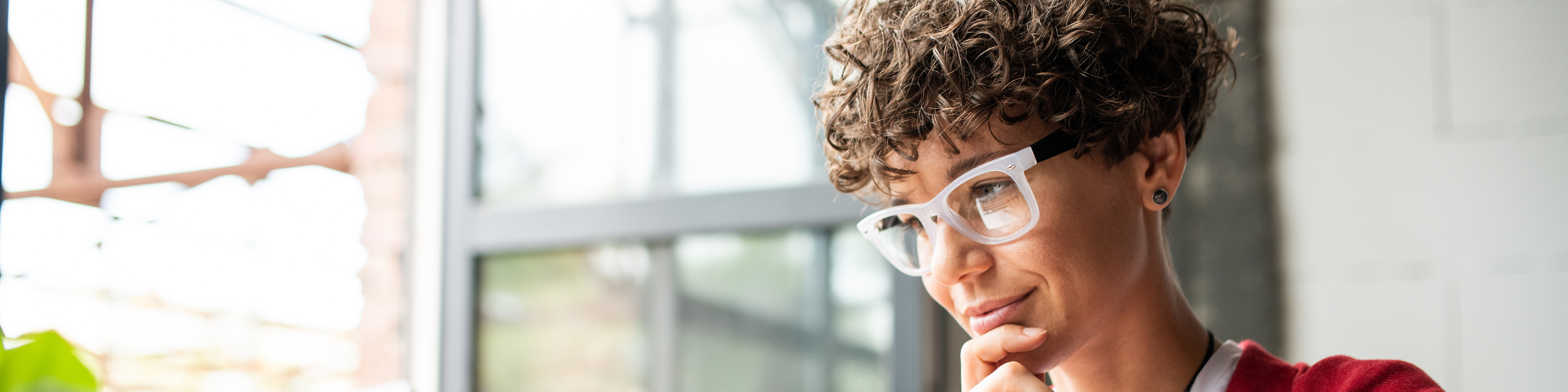 Busy young elegant woman in eyeglasses looking at laptop display